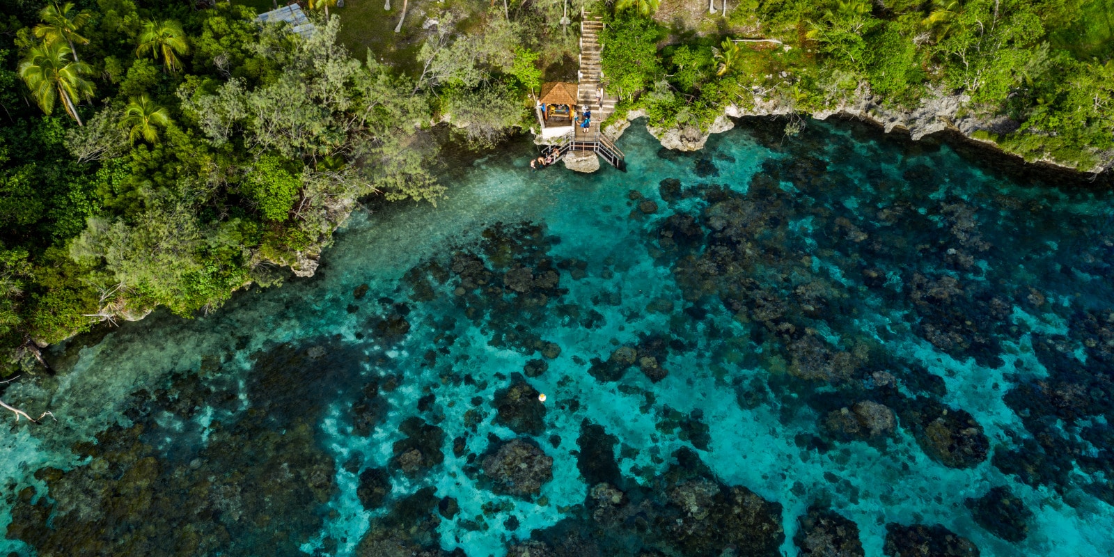 Vue aérienne sur une baie rocheuse donnant sur un lagon corallien en Nouvelle-Calédonie