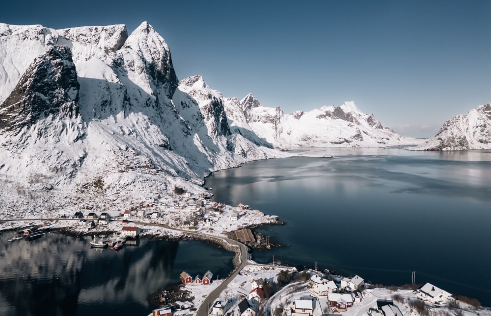 Vue aérienne sur un village entre mer et montagne sous la neige, village de Reine, Lofoten, Norvège.