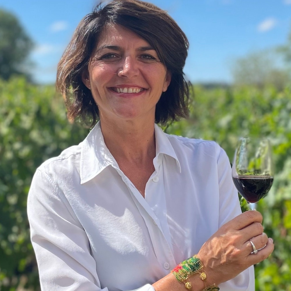 Portrait de Laetitia Ouspointour dans les vignes, un verre de vin à la main